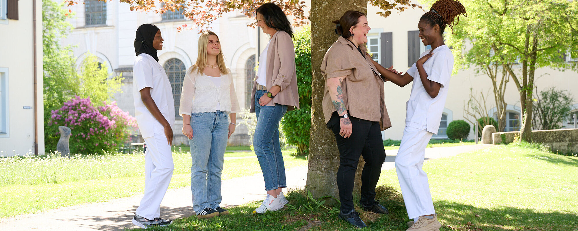 Eine junge Frau mit langen blonden Haaren und ein junger Mann im gelben T-Shirt sitzen auf Stufen vor einem Gebäude.