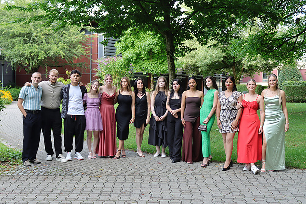 Festlich gekleidete junge Menschen haben sich zum Gruppenbild aufgestellt.